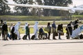Pessoas sentadas em um avião em roupas de proteção ou máscaras carregando bagagem