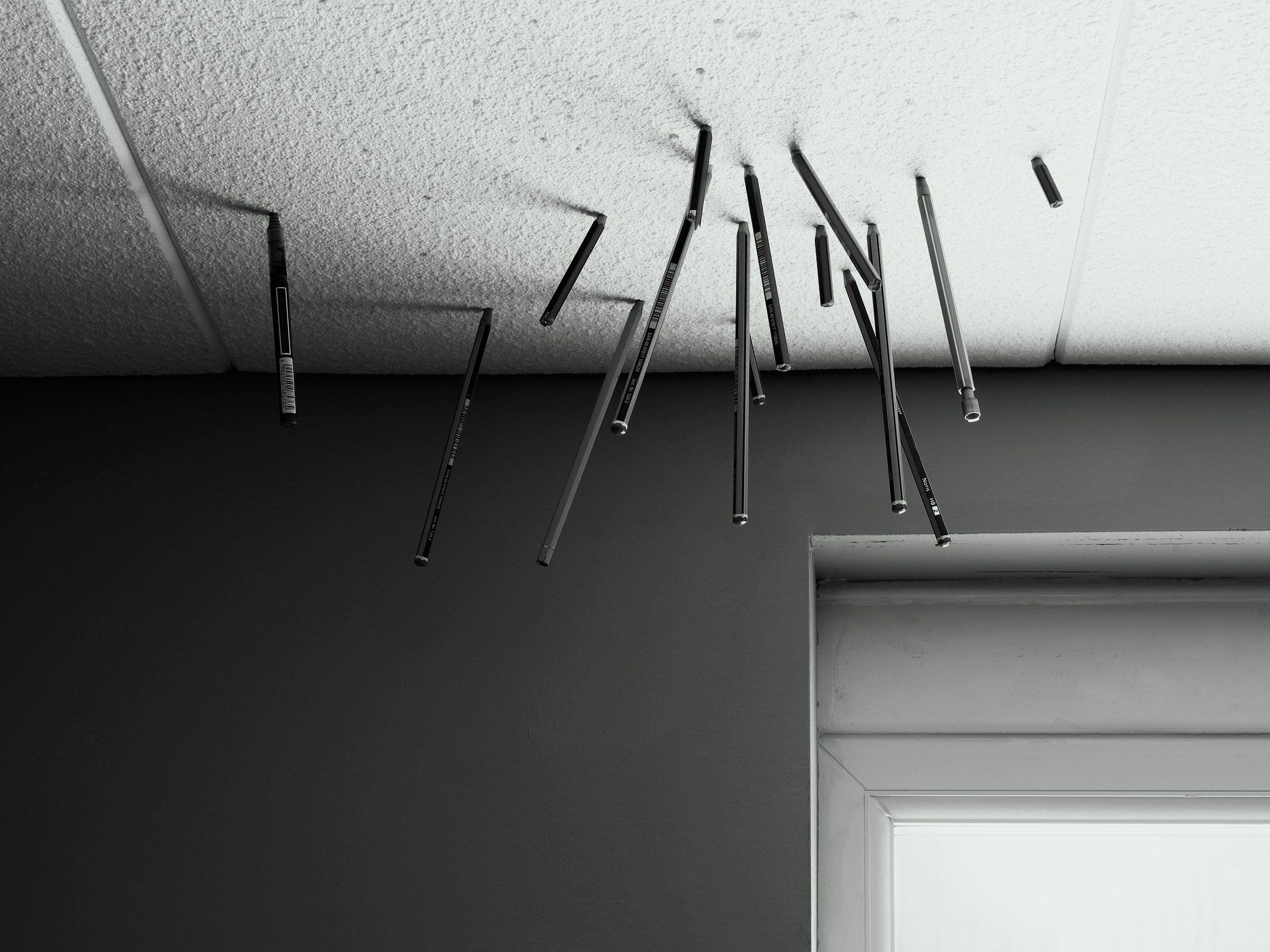 lápis presos nas telhas do teto do escritório