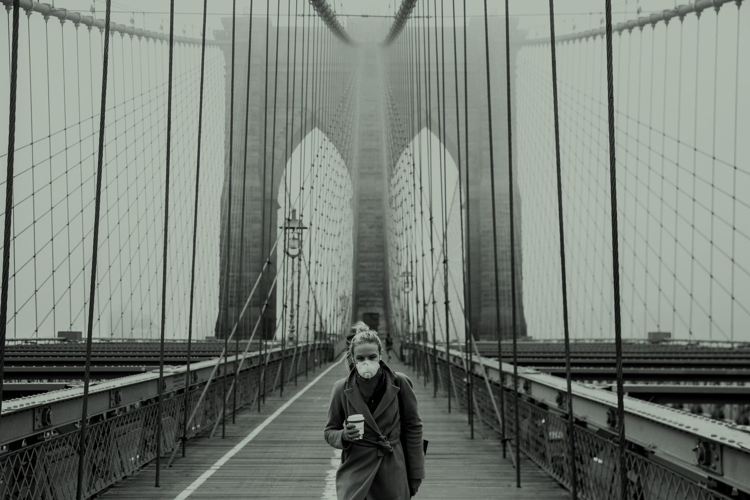 Uma mulher usando uma máscara protetora caminha pela Ponte do Brooklyn
