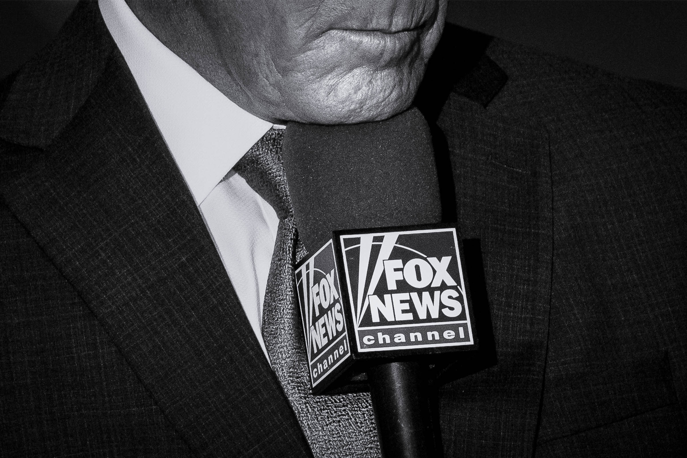O repórter do traje repousa com o queixo no microfone da Fox News