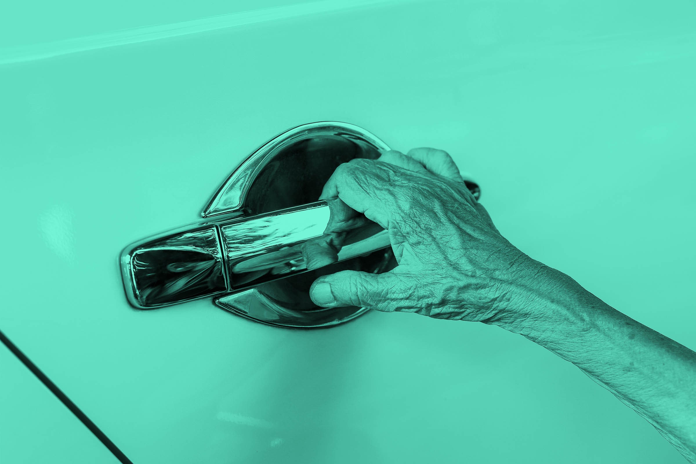 A mão de um homem idoso se estende para abrir a maçaneta da porta do carro