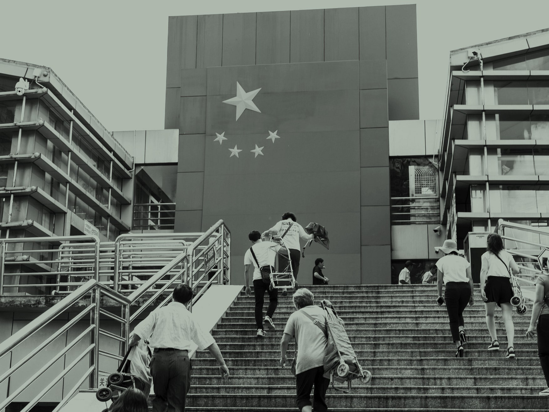 As pessoas sobem as escadas com carrinhos e outros objetos. A bandeira chinesa é desenhada no prédio.