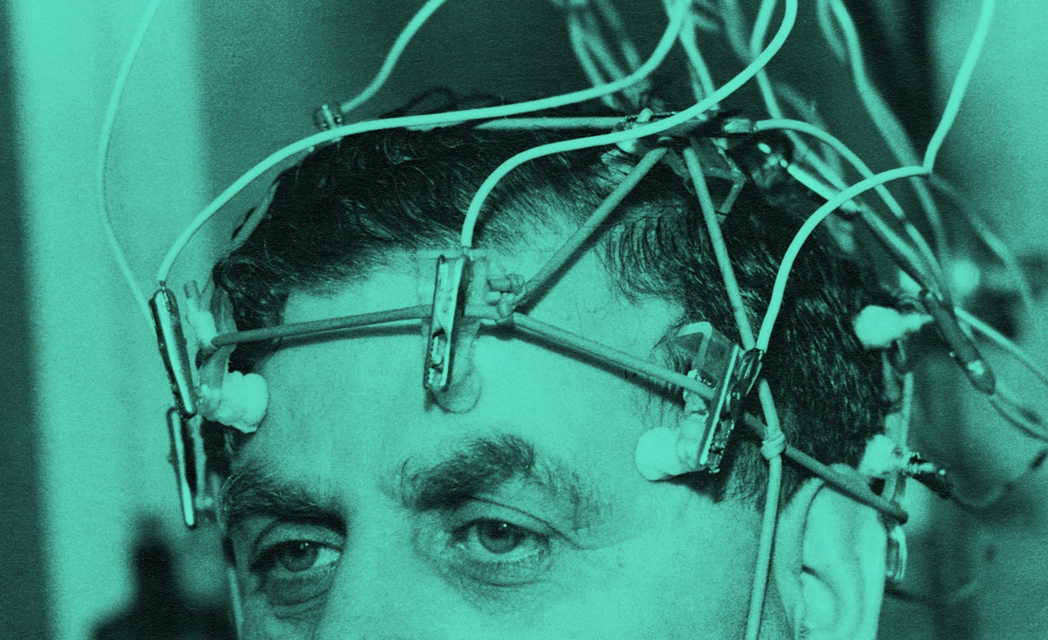 Um homem com fios presos à cabeça para um eletroencefalógrafo