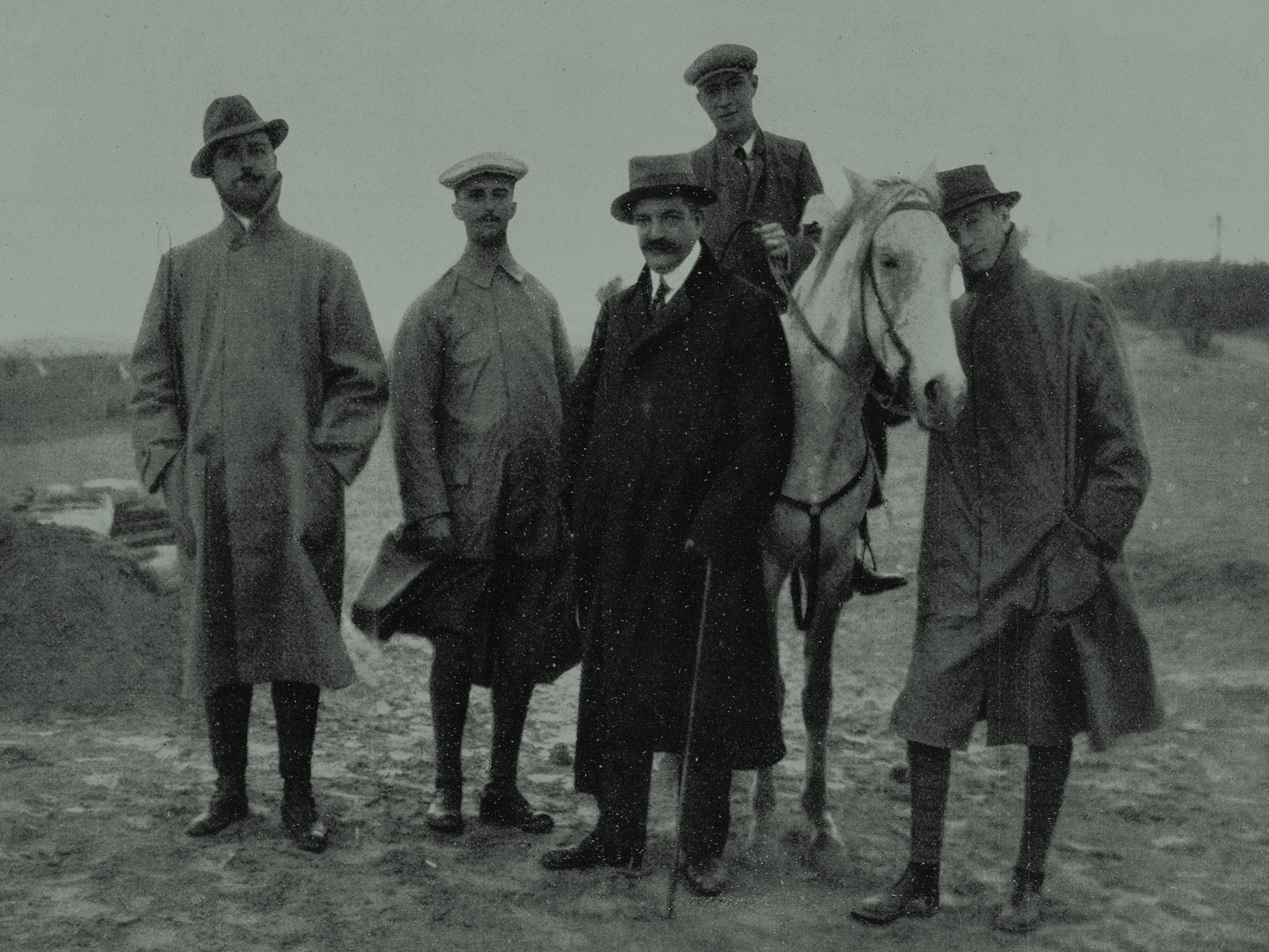 4 homens ficam e um homem em uma pose de cavalo para uma foto.