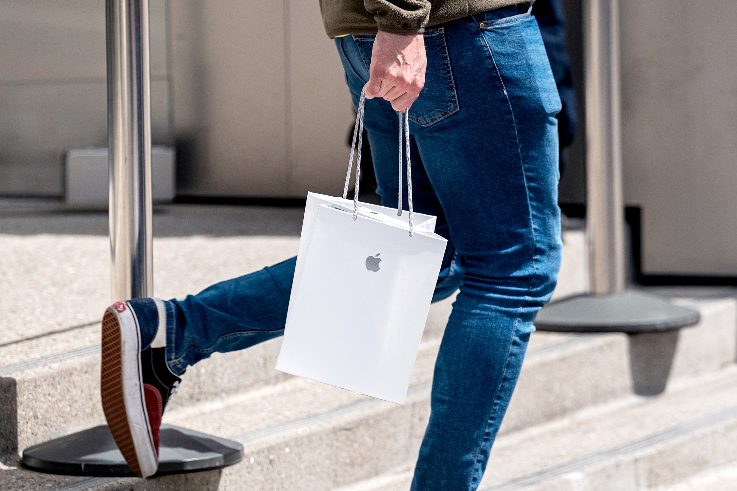 Uma pessoa vai com uma bolsa de compra na Apple Store