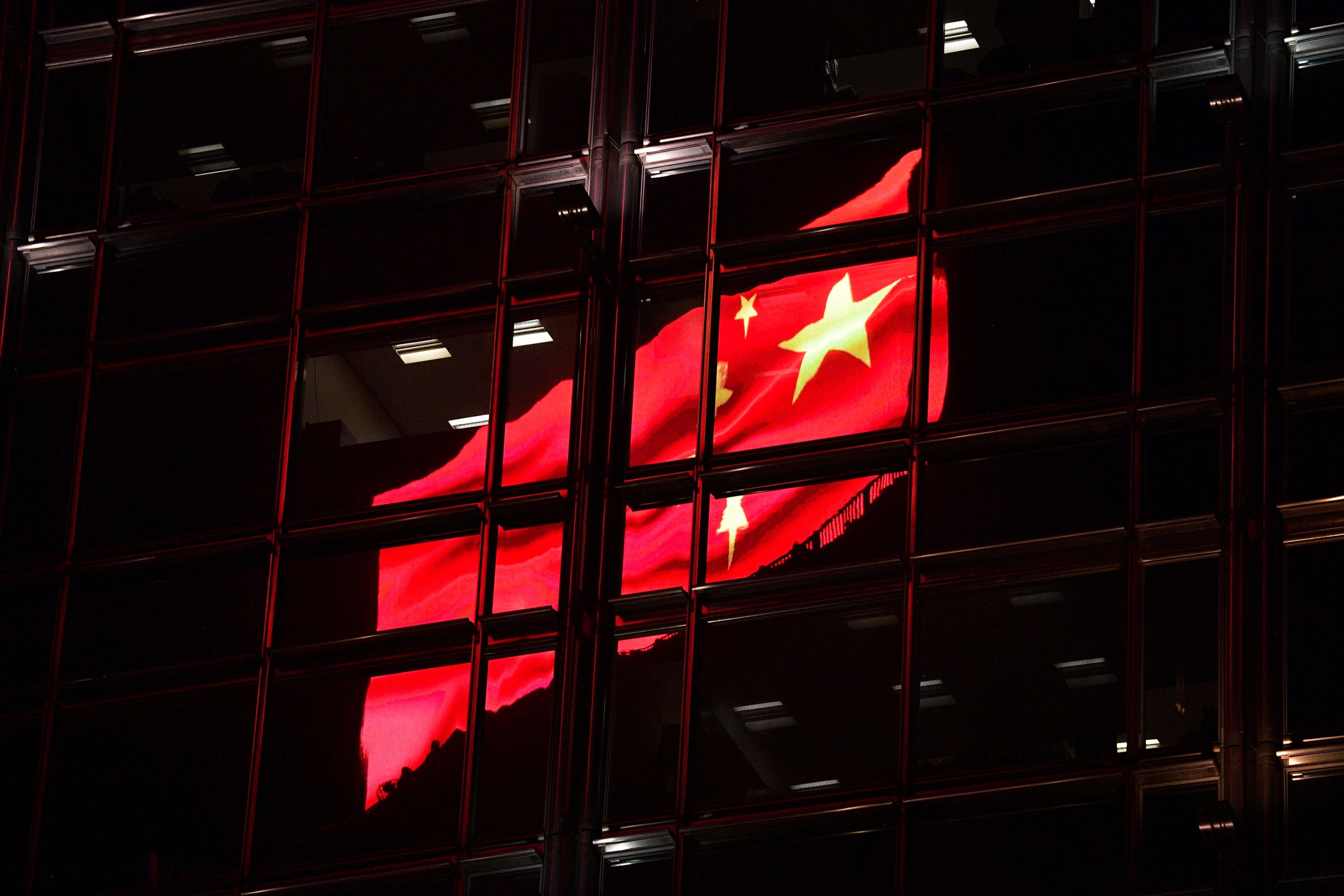 A bandeira chinesa retratada em um escudo de publicidade eletrônica se reflete no prédio em Hong Kong
