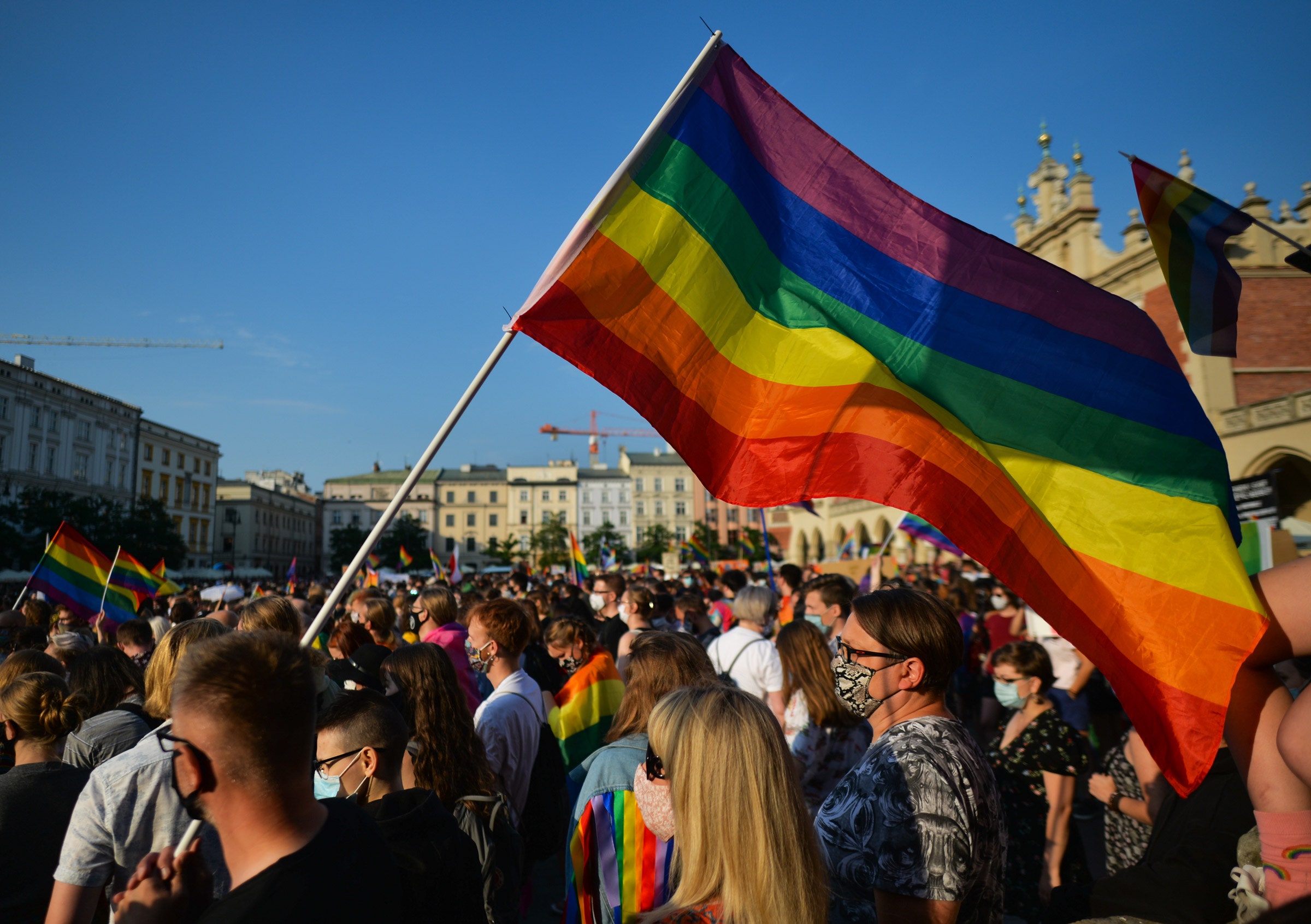 Ativistas pró-LGBT e seus apoiadores usando máscaras e segurando bandeiras de arco-íris
