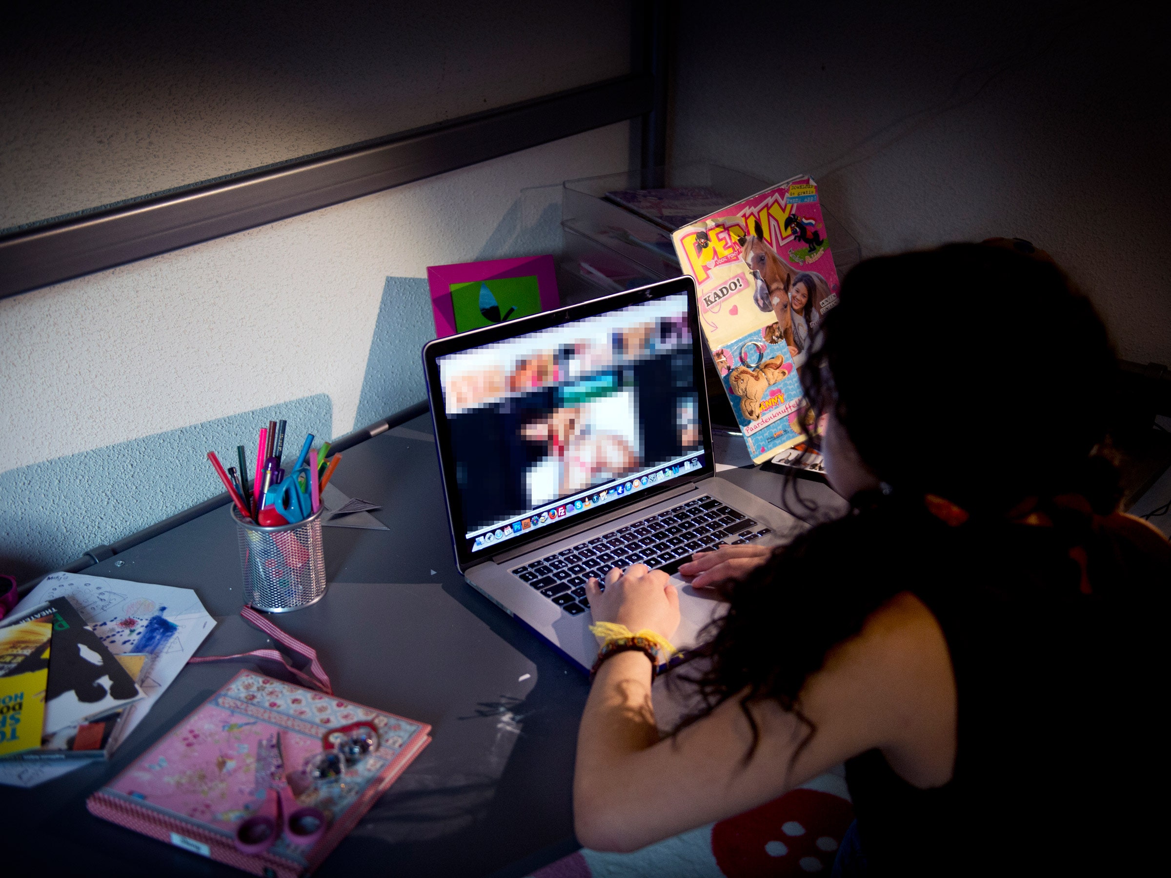 Um adolescente secretamente em seu quarto assiste pornografia na internet em um laptop