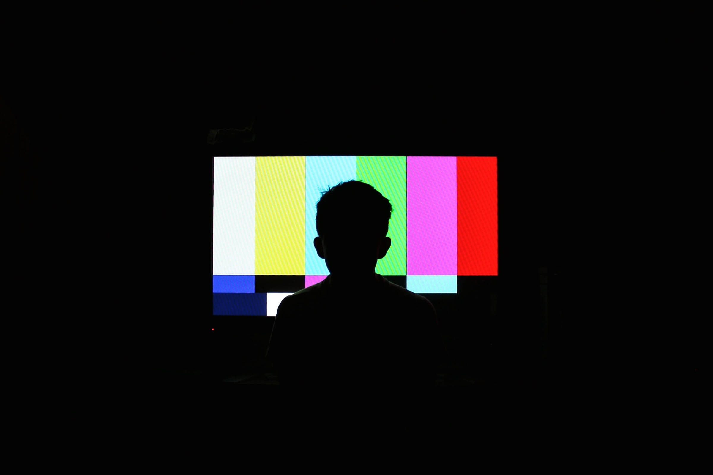 A silhueta de um jovem em frente à tela da TV