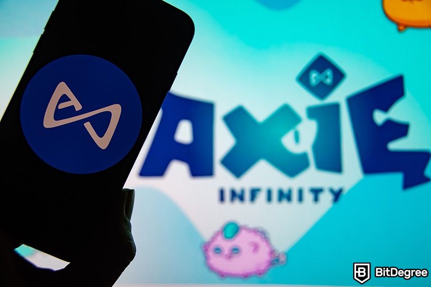 Os melhores jogos NFT: Axie Infinity Logo em segundo plano e, à sua frente, a pessoa segura o telefone.