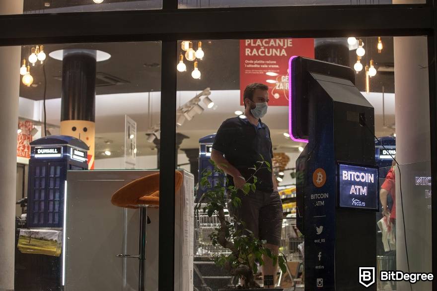 Como funciona um caixa eletrônico Bitcoin: um homem fica ao lado do caixa eletrônico.