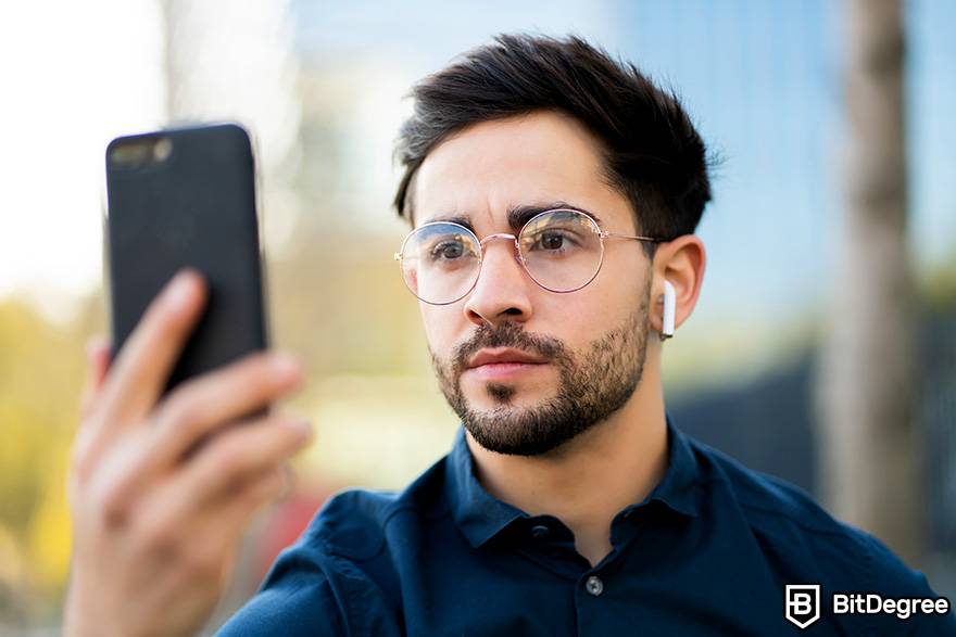 Como negociar criptomoeda: um homem usa verificação facial em seu telefone.