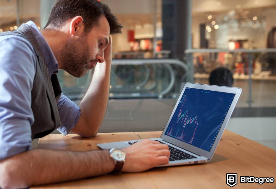 O que é Washing Trading Crypto: Um homem frustrado analisa os gráficos financeiros.